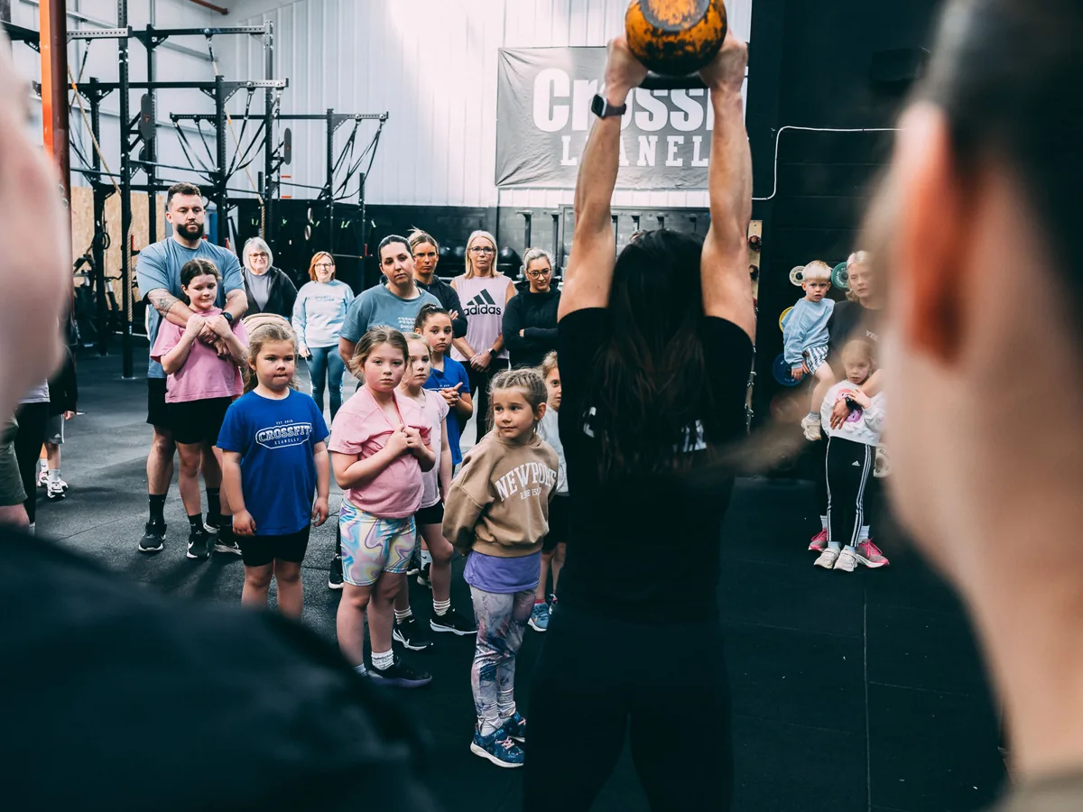 Kids class at CrossFit Llanelli, a child holding a ball overhead